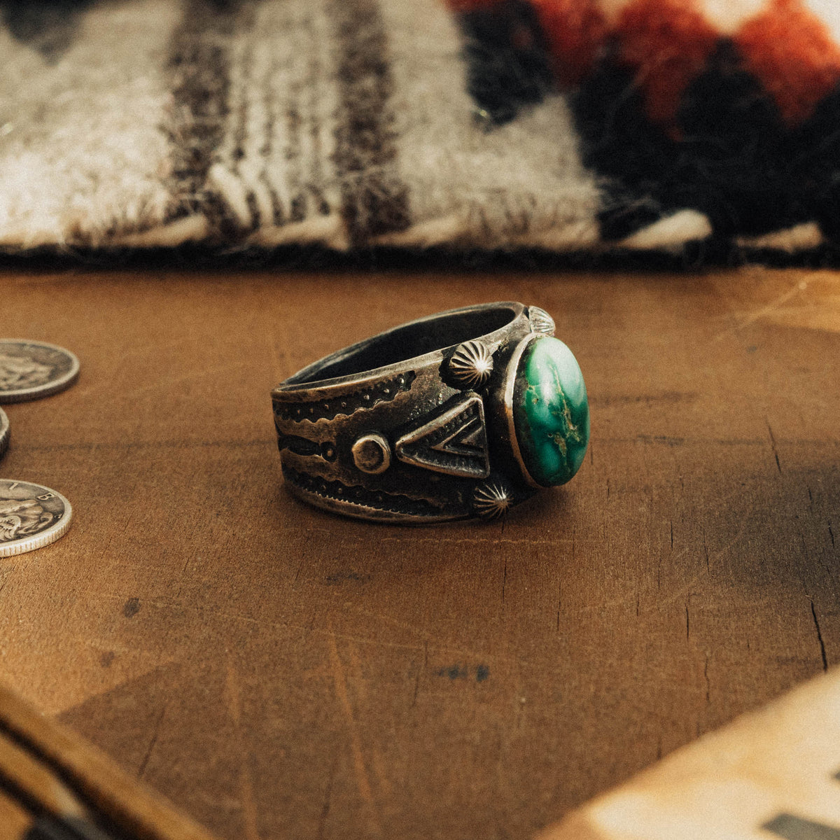 A hand-wrought sterling silver ring set with an oval Emerald Valley turquoise stone, its rich teal-green face threaded with golden-brown matrix, set in a smooth straight bezel — view 2