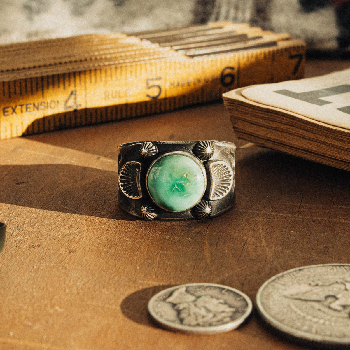 A hand-wrought sterling silver ring set with a round Emerald Valley turquoise stone, its soft mint-green face with subtle golden inclusions placed in a smooth straight bezel