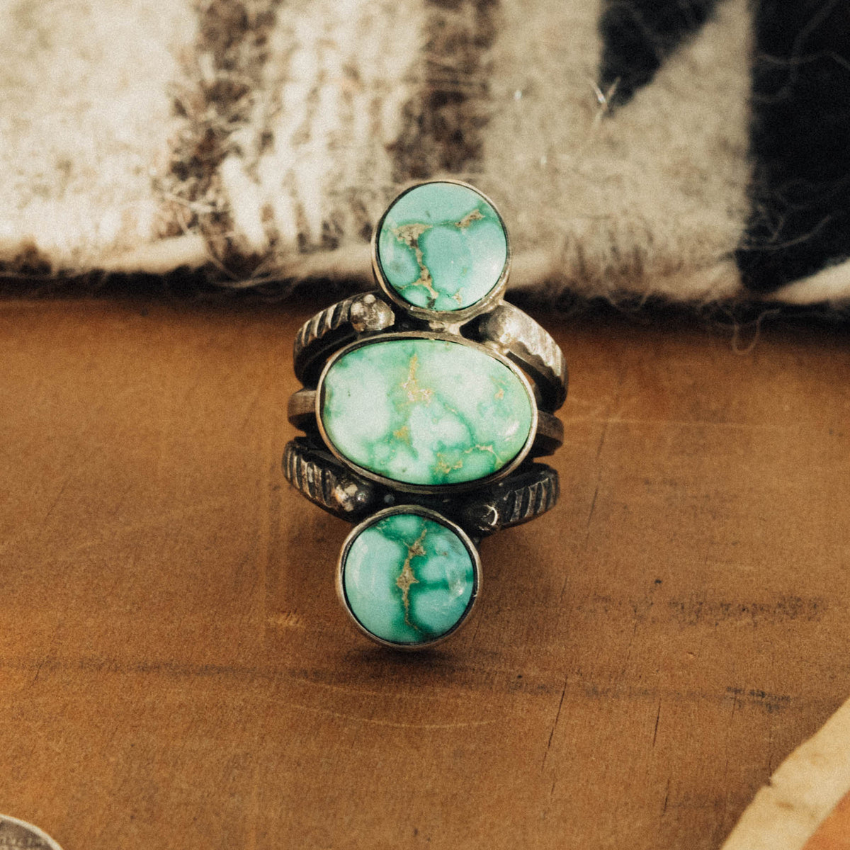 A hand-wrought sterling silver three-stone ring set in smooth straight bezels, each stone a bright mint-green Emerald Valley turquoise veined with golden-brown matrix