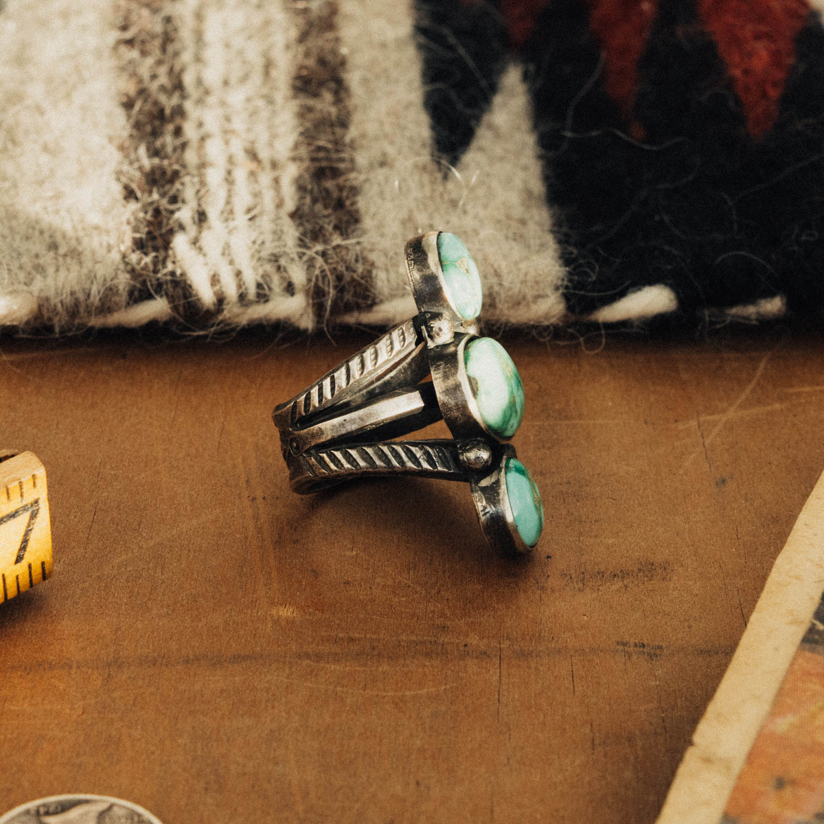 A hand-wrought sterling silver three-stone ring set in smooth straight bezels, each stone a bright mint-green Emerald Valley turquoise veined with golden-brown matrix — view 2