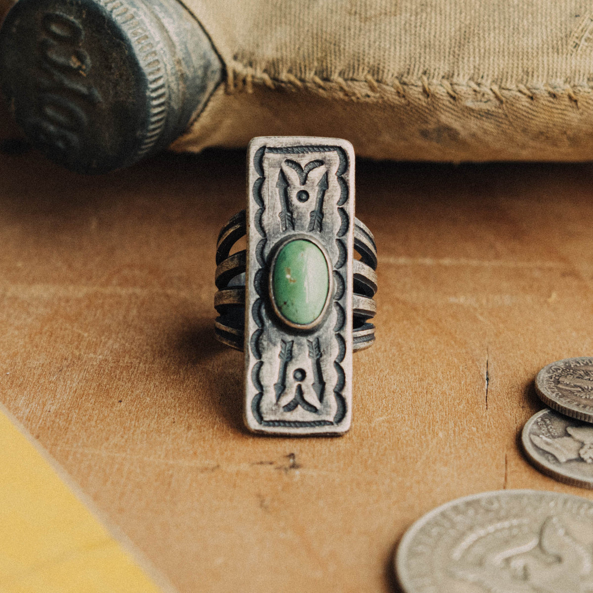 A hand-wrought sterling silver shield ring set with an oval Royston turquoise stone, its soft green face with subtle matrix, placed in a smooth straight bezel