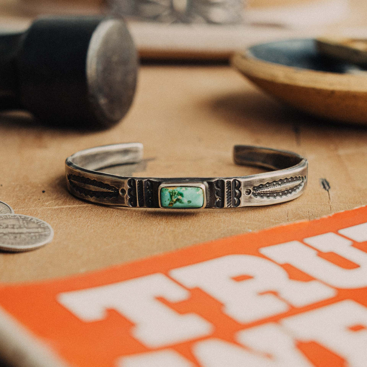 A hand-wrought sterling silver stacking cuff set with a rectangular Royston turquoise stone, its soft mint-green face touched with golden matrix, placed in a smooth straight bezel