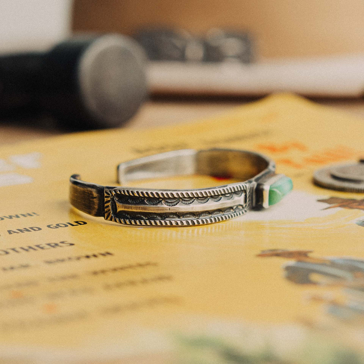 A hand-wrought sterling silver stacking cuff set with a rectangular Royston turquoise stone, its vivid true-green face threaded with warm rust-brown matrix, placed in a smooth straight bezel