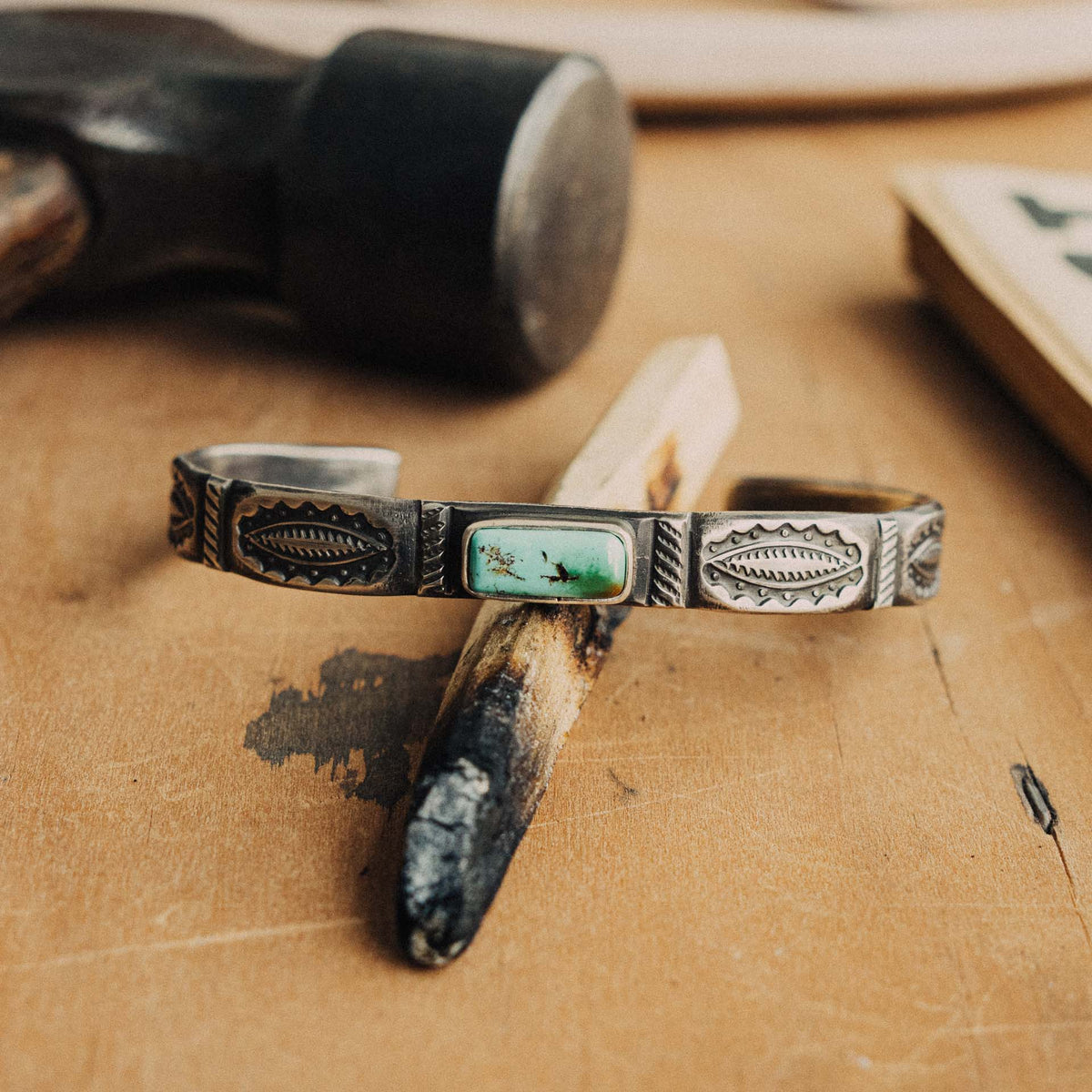 A hand-wrought sterling silver stacking cuff set with a rectangular Royston turquoise stone, its soft blue-green face with subtle dark matrix, placed in a smooth straight bezel
