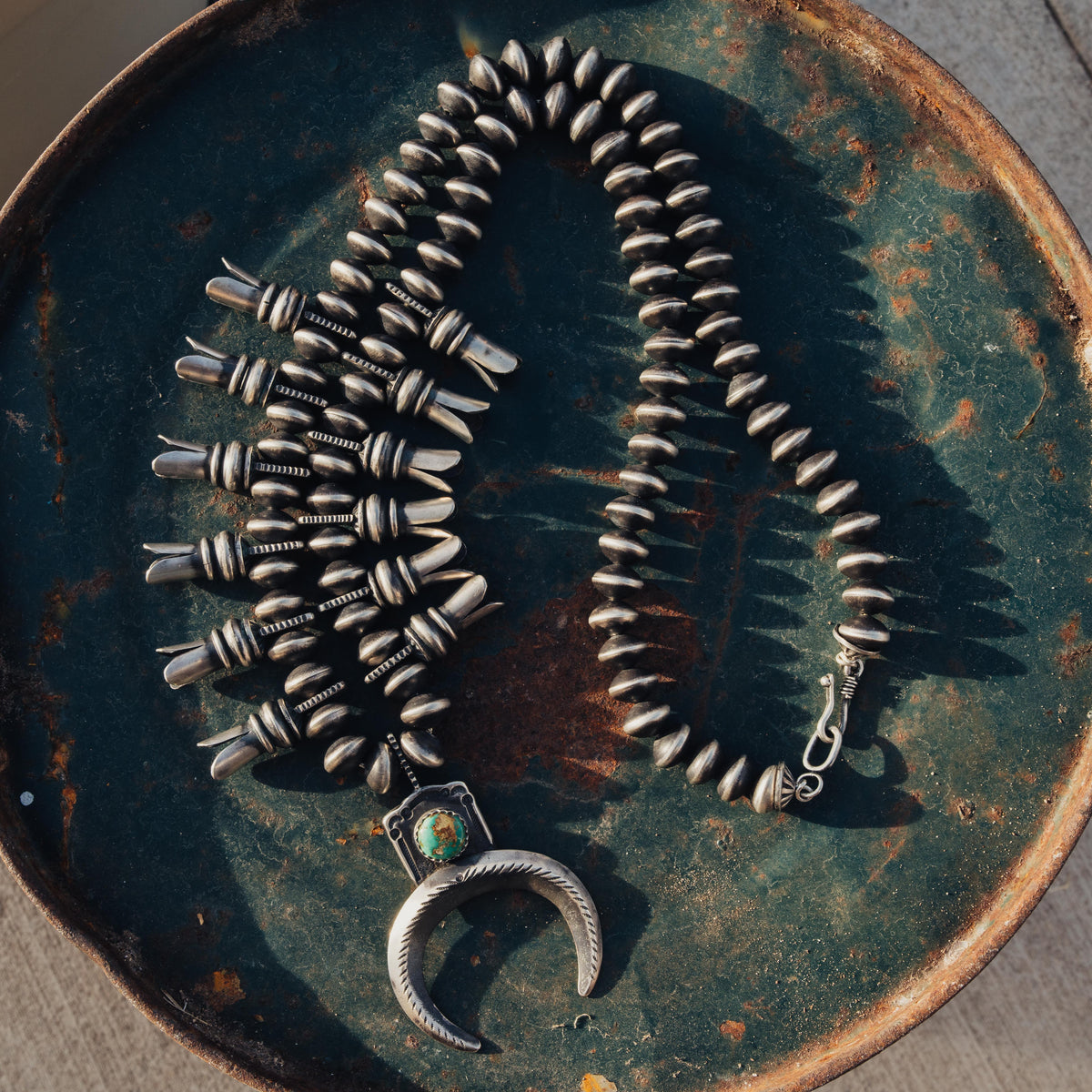 A hand-wrought sterling silver squash blossom necklace strung with substantial beads — view 2