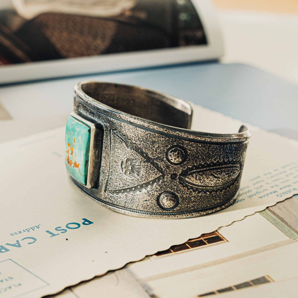 A wide tufa cast sterling silver cuff centered on a rectangular Royston turquoise stone, its soft green face threaded with rust-brown matrix, set in a smooth bezel — view 2