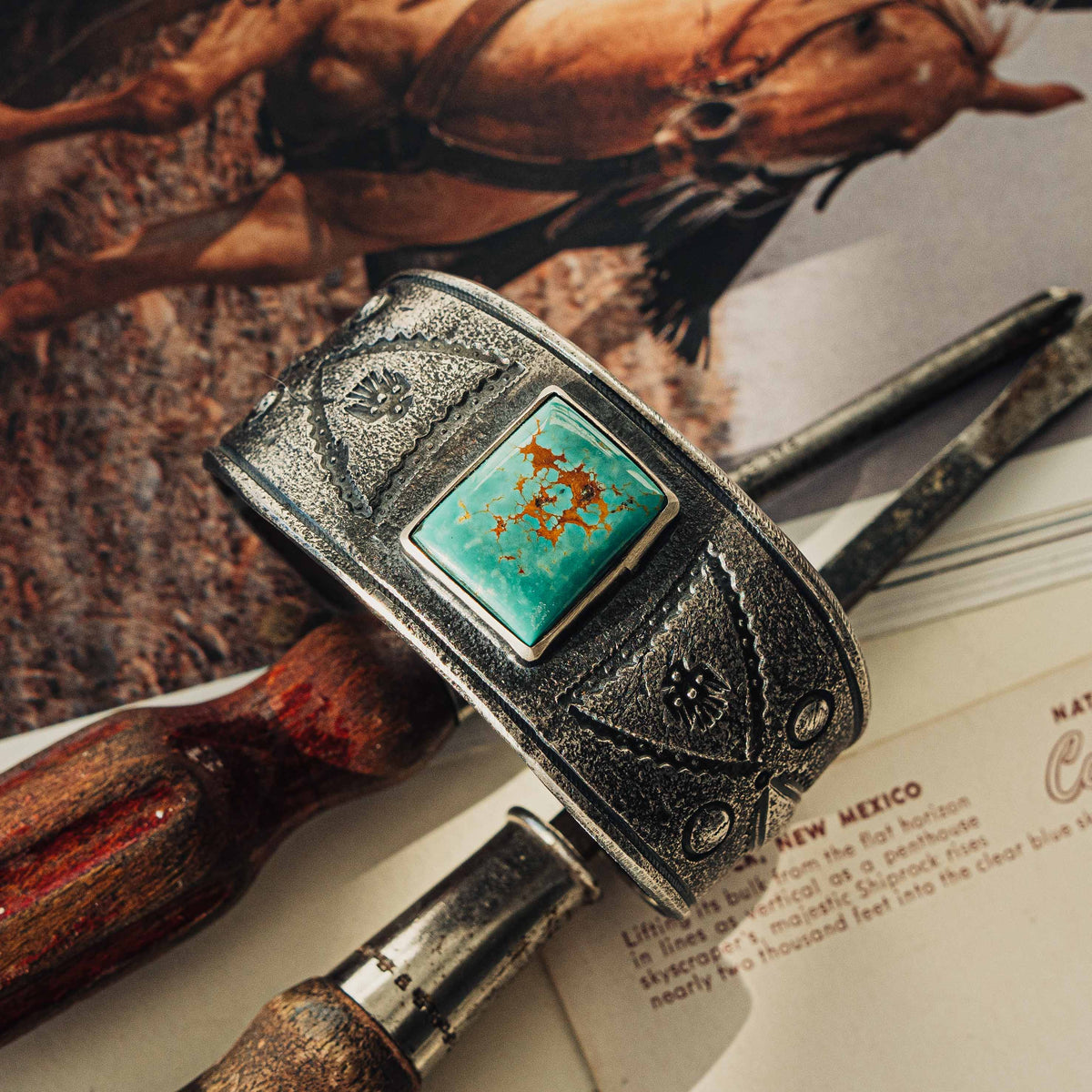 A wide tufa cast sterling silver cuff centered on a rectangular Royston turquoise stone, its soft green face threaded with rust-brown matrix, set in a smooth bezel — view 3