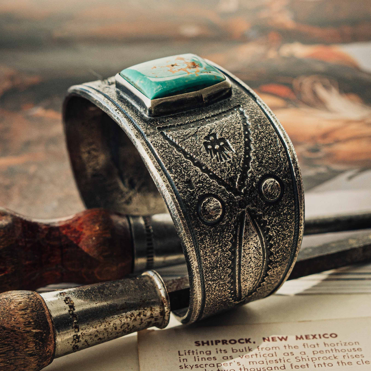 A wide tufa cast sterling silver cuff centered on a rectangular Royston turquoise stone, its soft green face threaded with rust-brown matrix, set in a smooth bezel — view 4