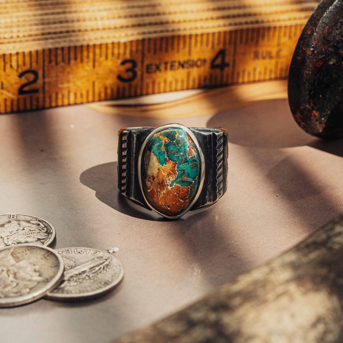 A heavy hand-wrought sterling silver ring centered on an oval Royston turquoise stone, its blend of sea-green and golden-brown matrix set in a smooth straight bezel
