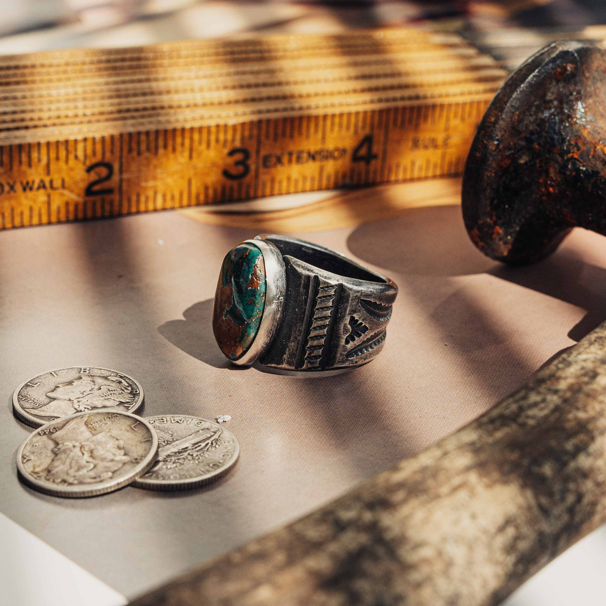 A heavy hand-wrought sterling silver ring centered on an oval Royston turquoise stone, its blend of sea-green and golden-brown matrix set in a smooth straight bezel — view 2