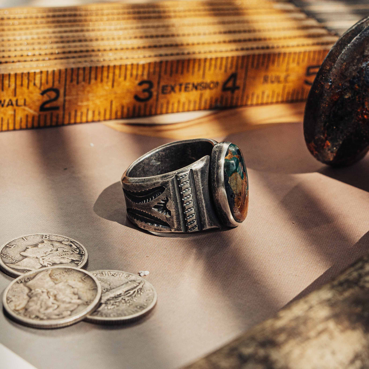 A heavy hand-wrought sterling silver ring centered on an oval Royston turquoise stone, its blend of sea-green and golden-brown matrix set in a smooth straight bezel — view 3