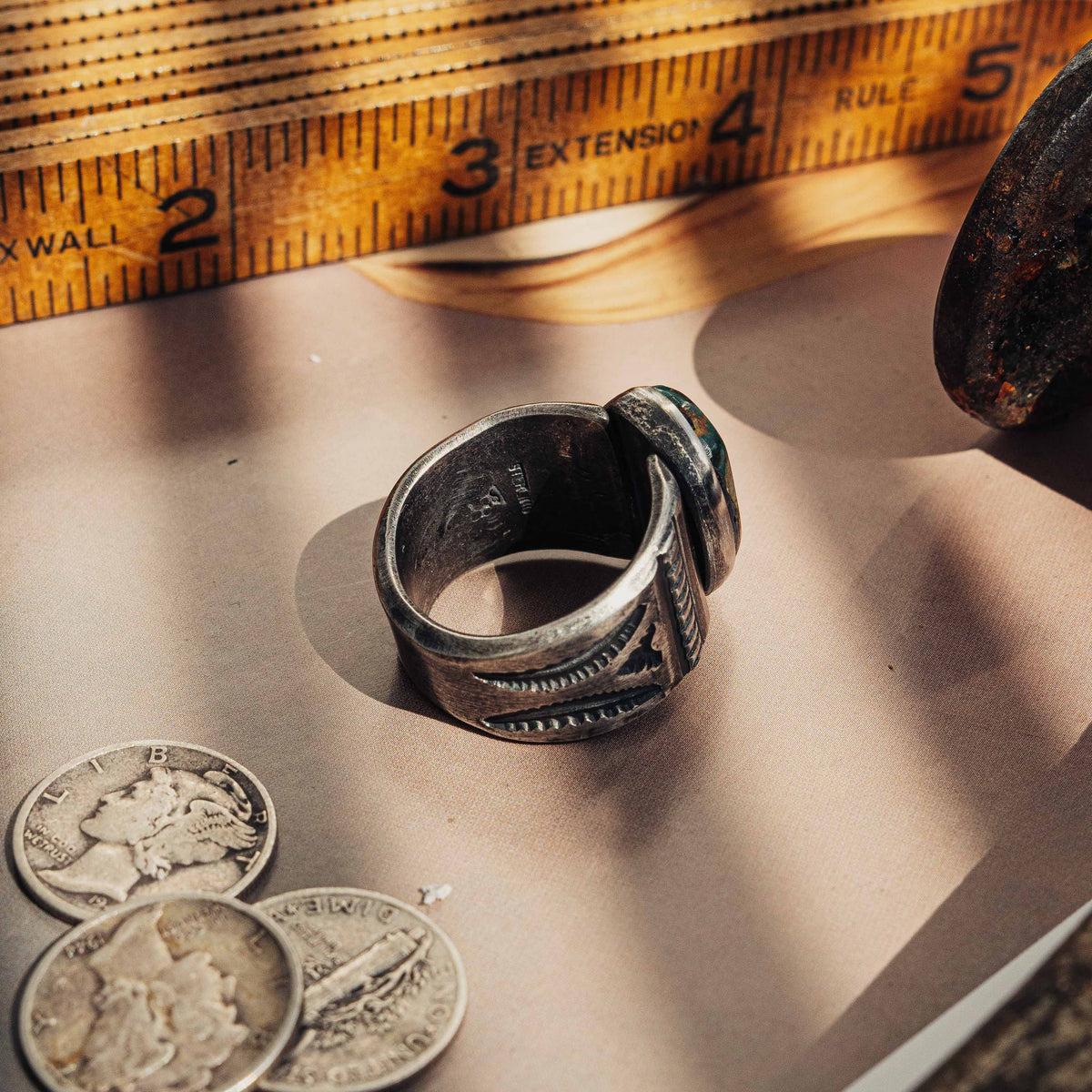 A heavy hand-wrought sterling silver ring centered on an oval Royston turquoise stone, its blend of sea-green and golden-brown matrix set in a smooth straight bezel — view 4
