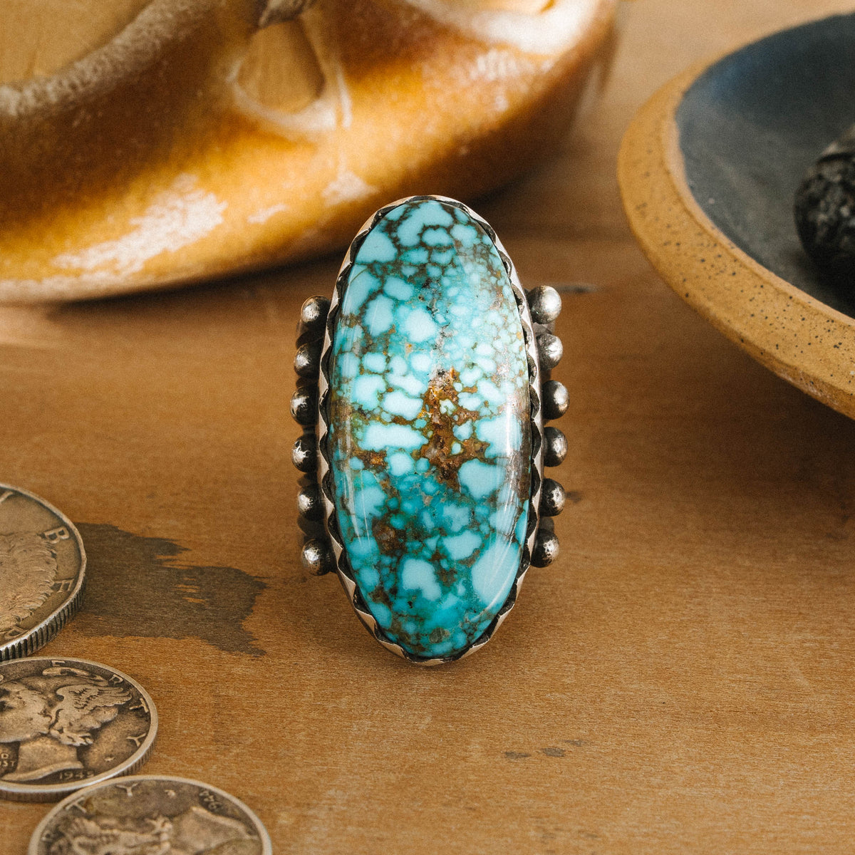 A high-grade Kingman Water Web turquoise stone sits in a hand-filed serrated bezel, set atop a six-prong split shank accented with silver beads and finished with a hand-stamped underside