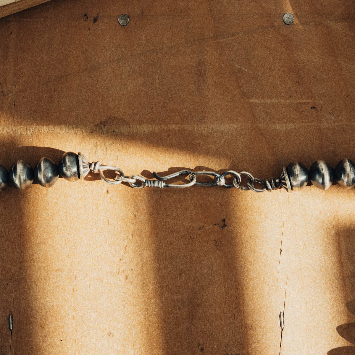 A traditional sterling silver squash blossom necklace, strung with substantial oxidized silver beads — view 2