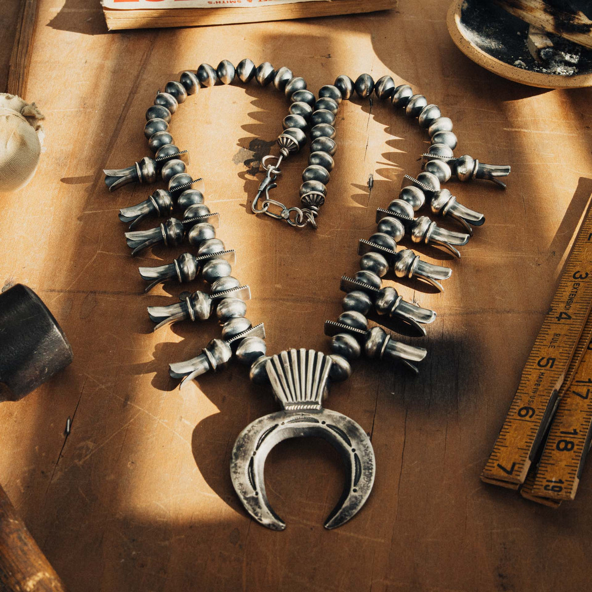 A traditional sterling silver squash blossom necklace, strung with substantial oxidized silver beads