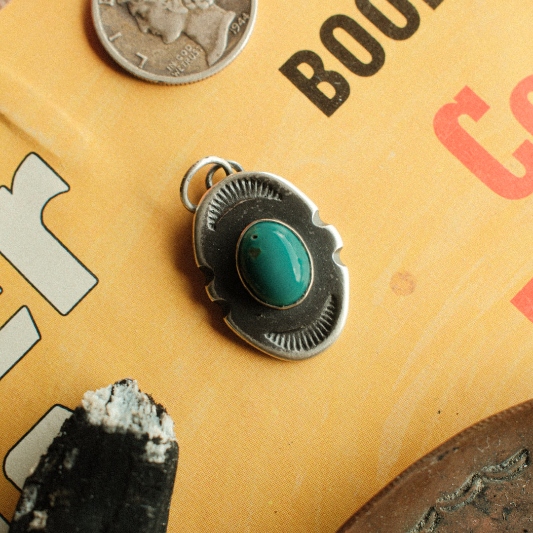 An oval sterling silver shield pendant with notched sides, set with sea-green Carico Lake turquoise. Hand-finished in our shop with a strong Southwest patina.