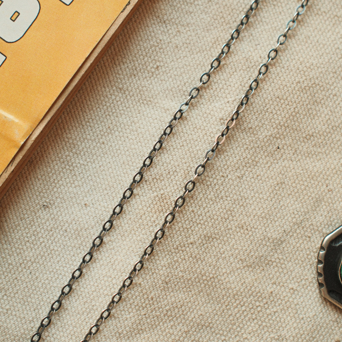 A lightweight sterling silver cable chain with flat oval links in 16 to 20 inch lengths, finished with a lobster clasp and a hand-applied patina.