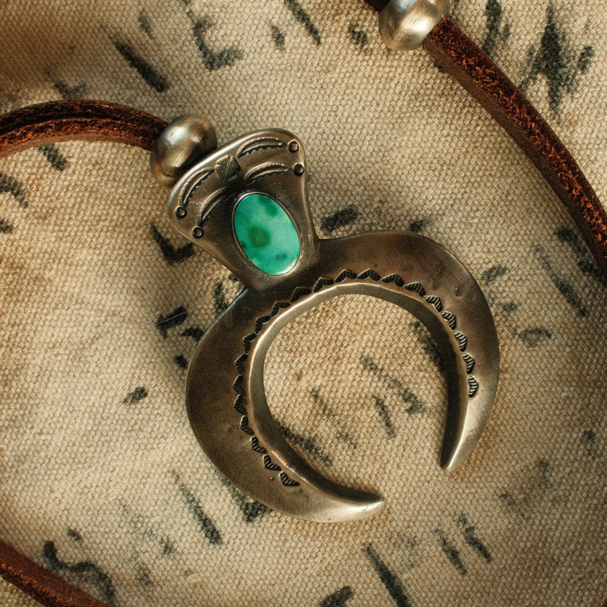 A one-of-a-kind tufa-cast Naja, thunderbird-stamped and set with a 9×15mm premium piece of Fox turquoise, on brown leather with two handmade silver adjusting beads — view 4