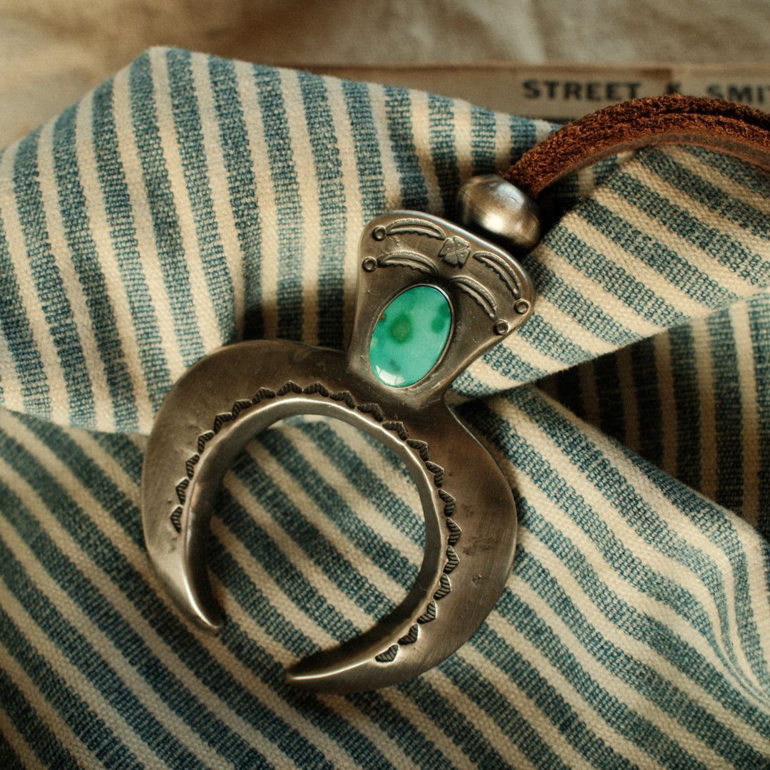 A one-of-a-kind tufa-cast Naja, thunderbird-stamped and set with a 9×15mm premium piece of Fox turquoise, on brown leather with two handmade silver adjusting beads — view 2
