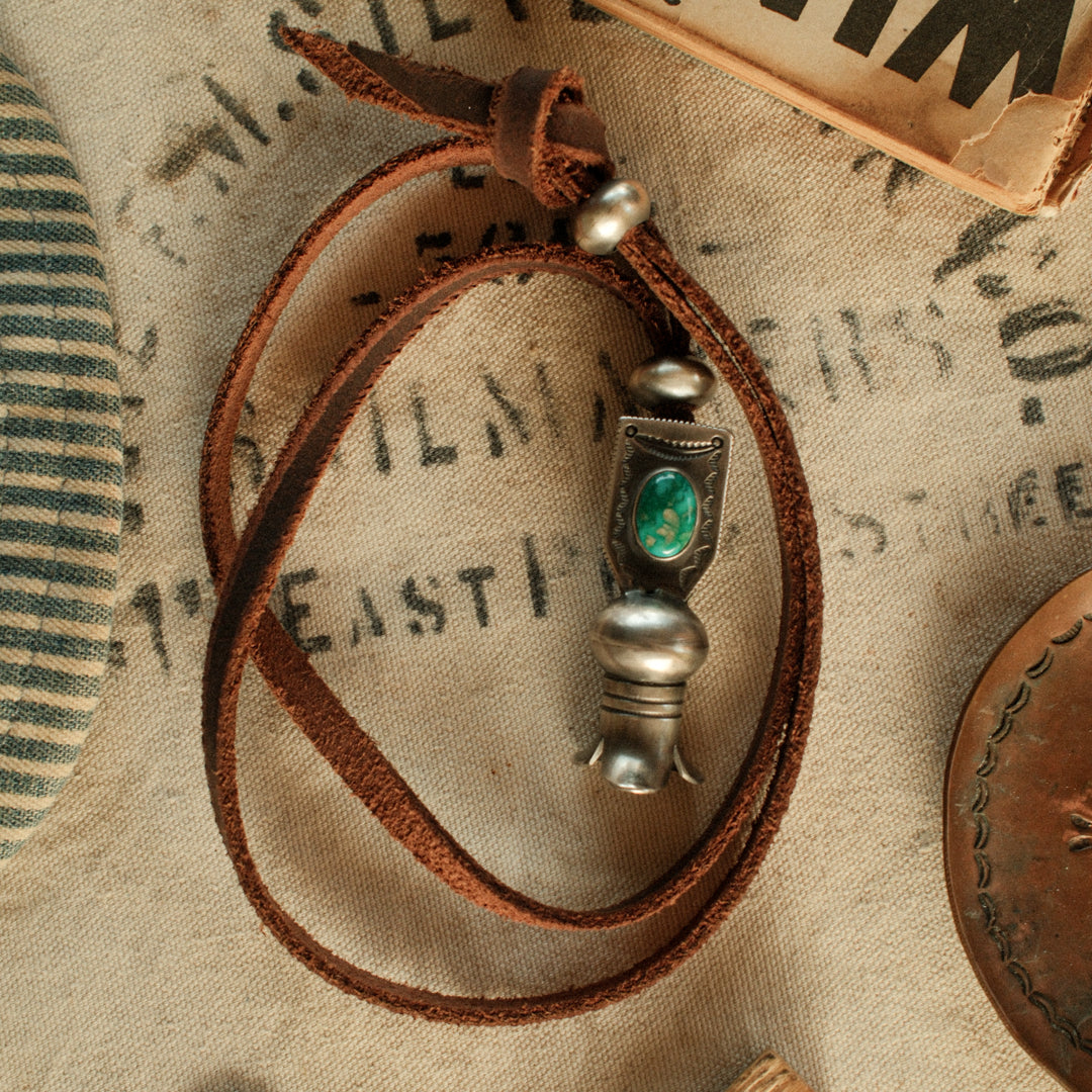 A one-of-a-kind hand-stamped squash blossom set with an 8×12mm premium piece of Fox turquoise, on brown leather with two handmade silver adjusting beads — view 2