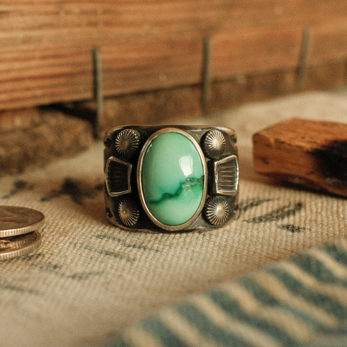 A one-of-a-kind 10×15mm Fox turquoise in a smooth bezel between stamped panels and starburst conchos, on a wide tapering band