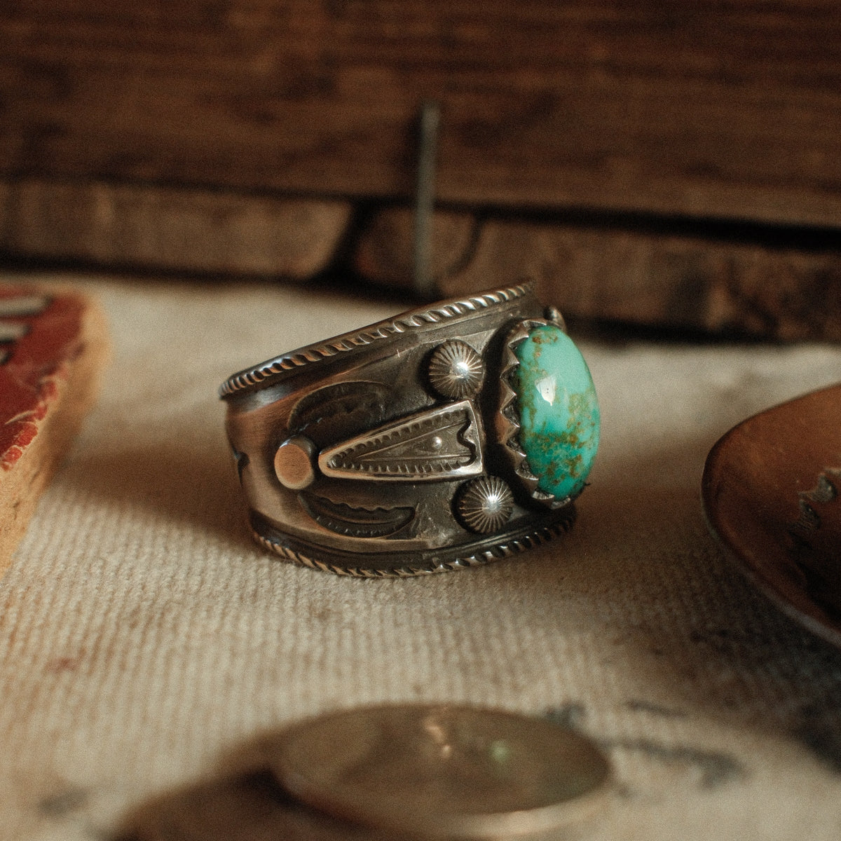A one-of-a-kind 9×13mm Fox turquoise in a filed serrated bezel with stamped arrowhead panels, starburst conchos, channel work and a hatched border — view 2