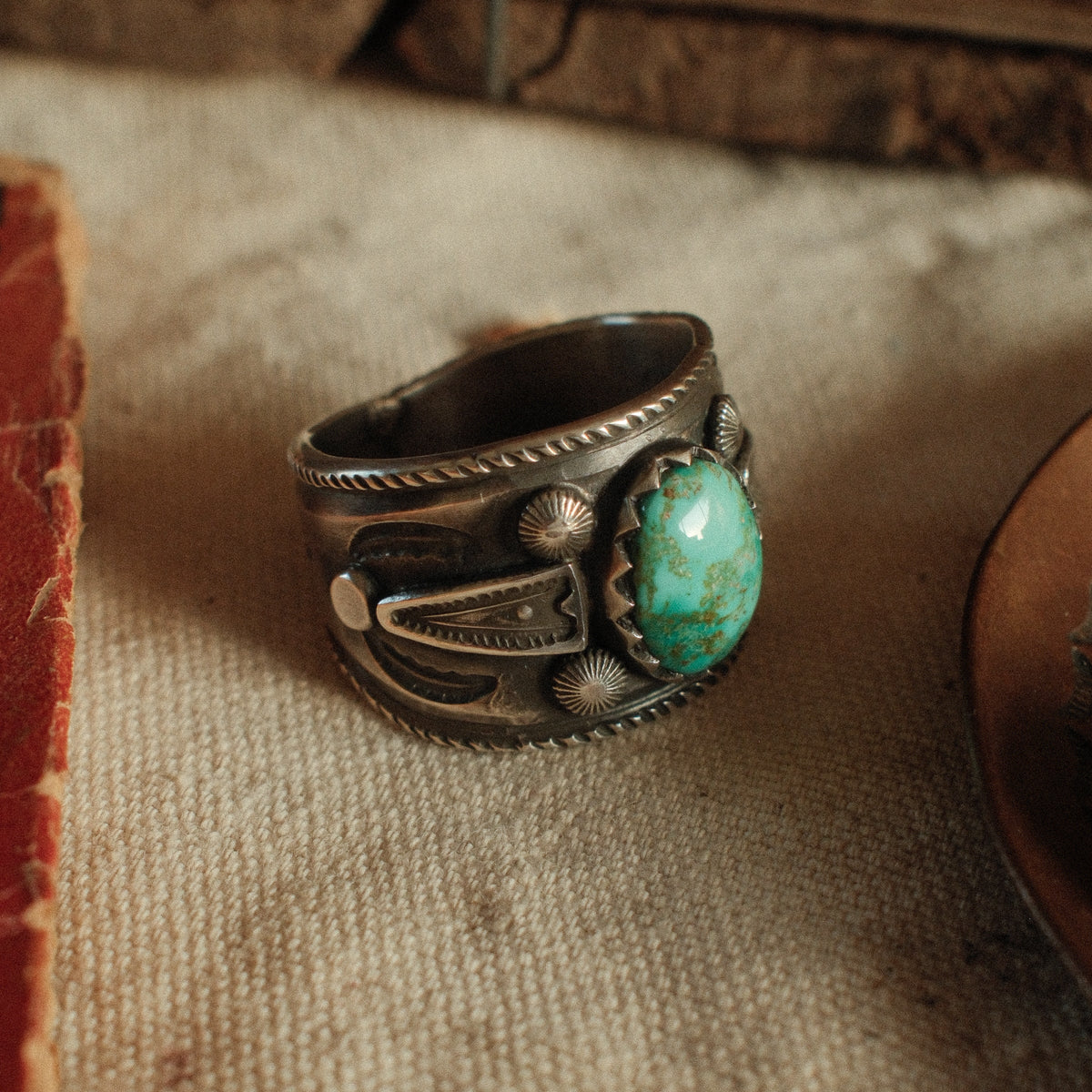 A one-of-a-kind 9×13mm Fox turquoise in a filed serrated bezel with stamped arrowhead panels, starburst conchos, channel work and a hatched border — view 3