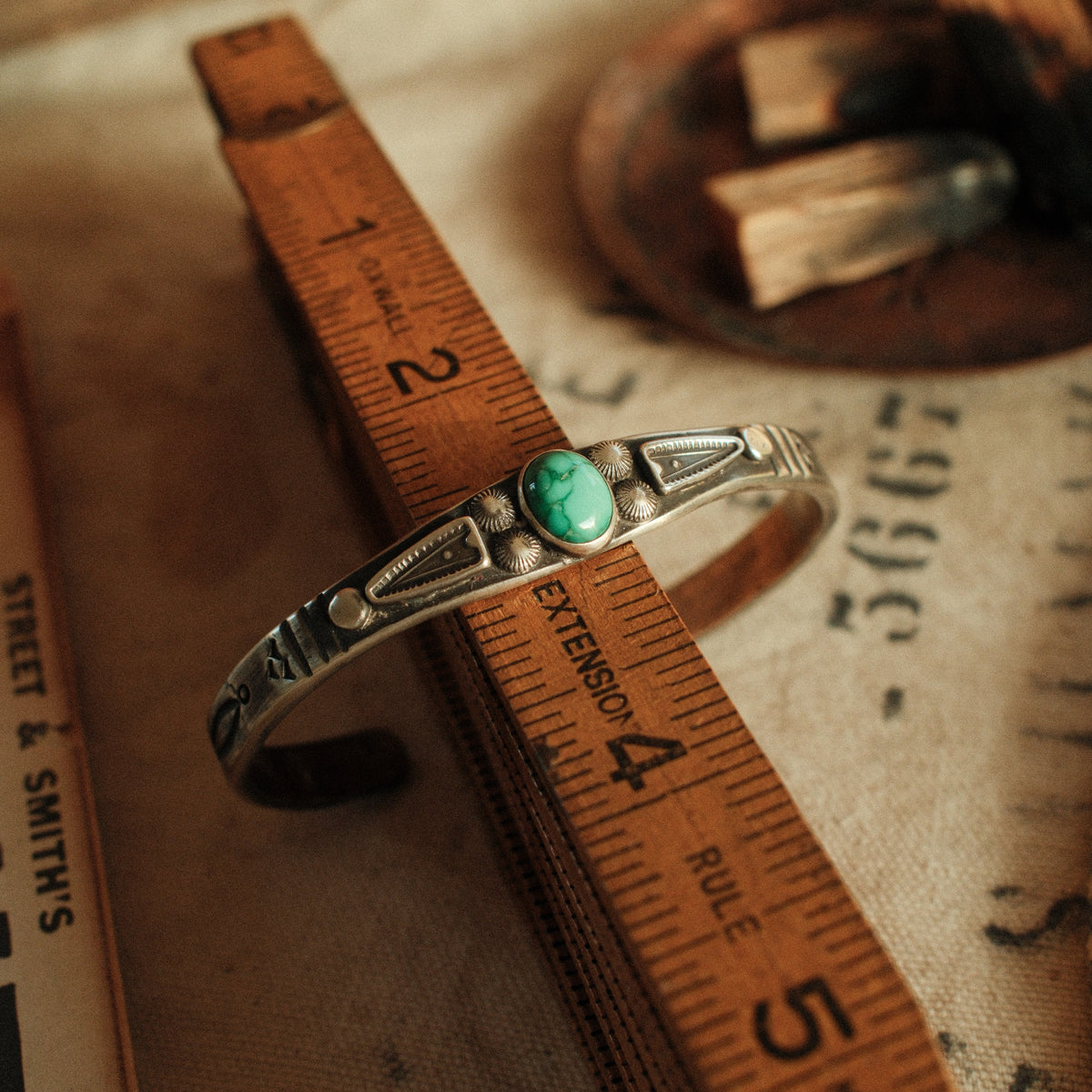 A one-of-a-kind tufa-cast stacking cuff with a 7×9mm Fox turquoise in a hand filed serrated bezel between stamped arrowhead panels — view 3