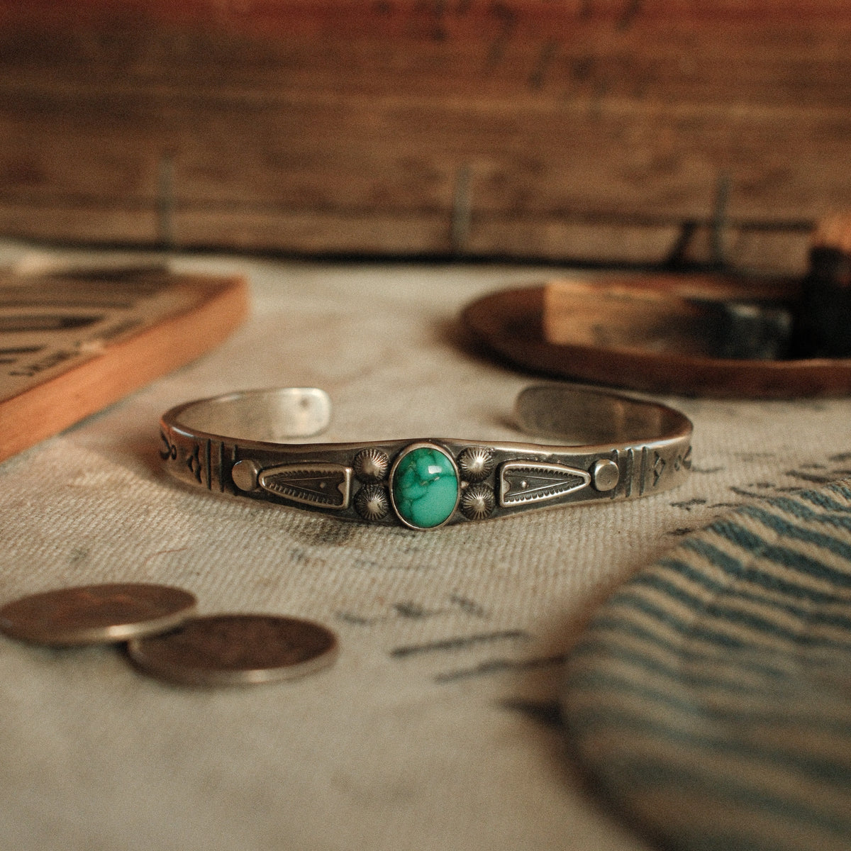 A one-of-a-kind tufa-cast stacking cuff with a 7×9mm Fox turquoise in a hand filed serrated bezel between stamped arrowhead panels