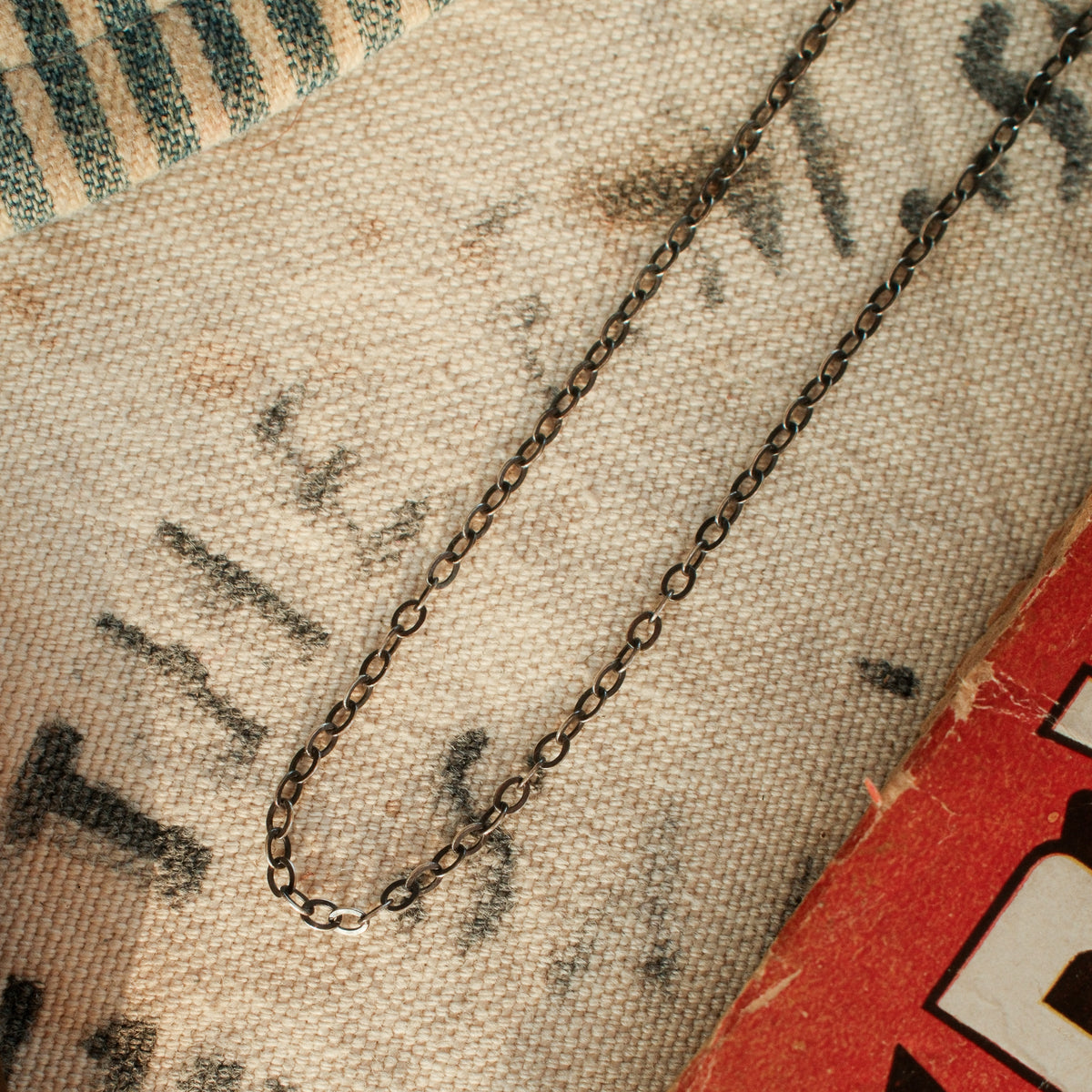 A lightweight sterling silver cable chain with flat oval links in 16 to 20 inch lengths, finished with a lobster clasp and a hand-applied patina.