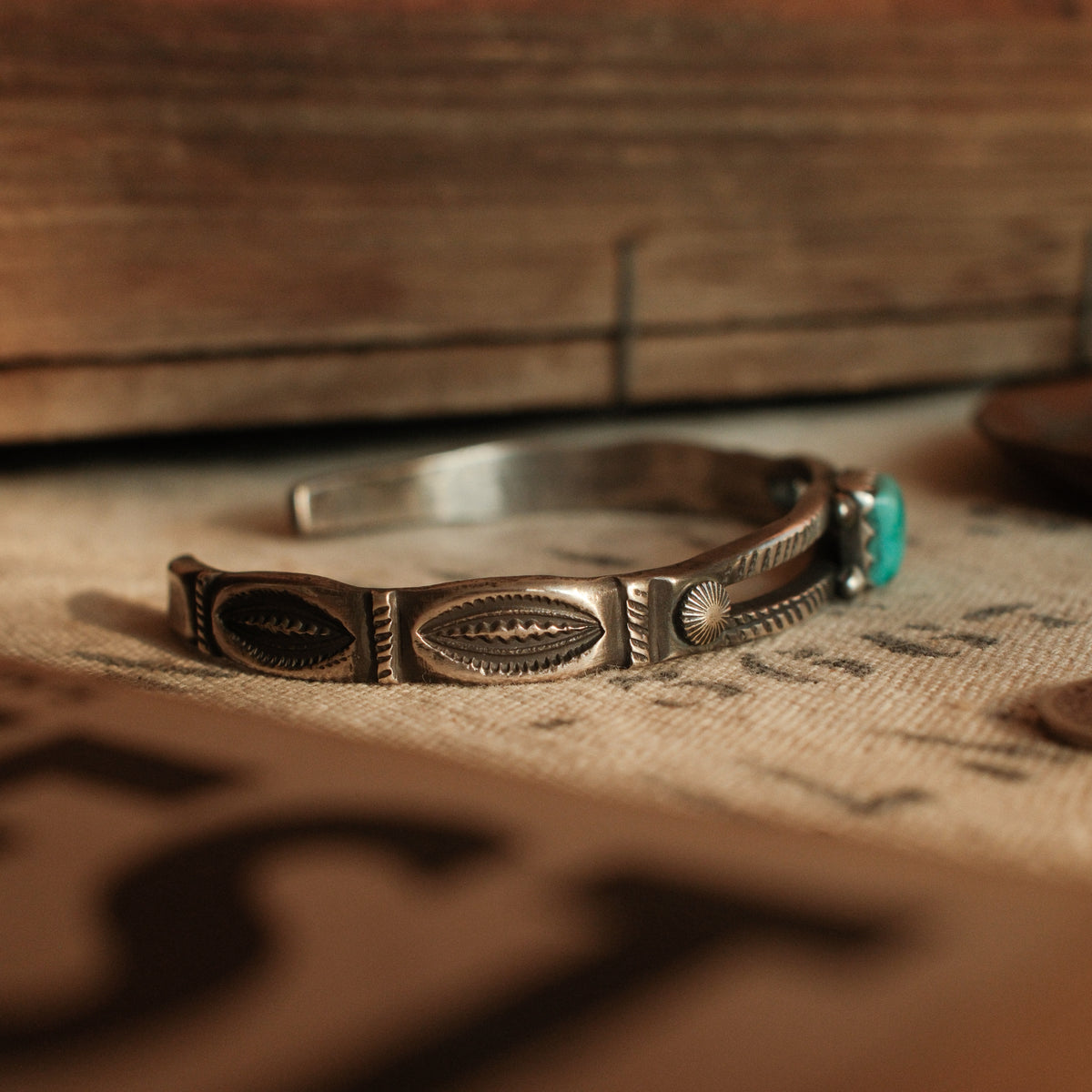 A one-of-a-kind tufa-cast split cuff with an 8×10mm Fox turquoise in a hand filed serrated bezel between twin hatched bars — view 3
