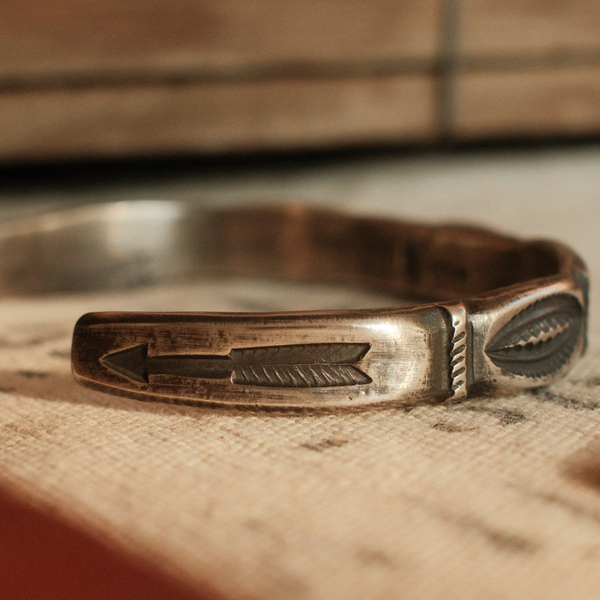 A one-of-a-kind tufa-cast stacking cuff with a 5×12mm Fox turquoise in a hand filed serrated bezel, large arrows struck inside each terminal — view 3