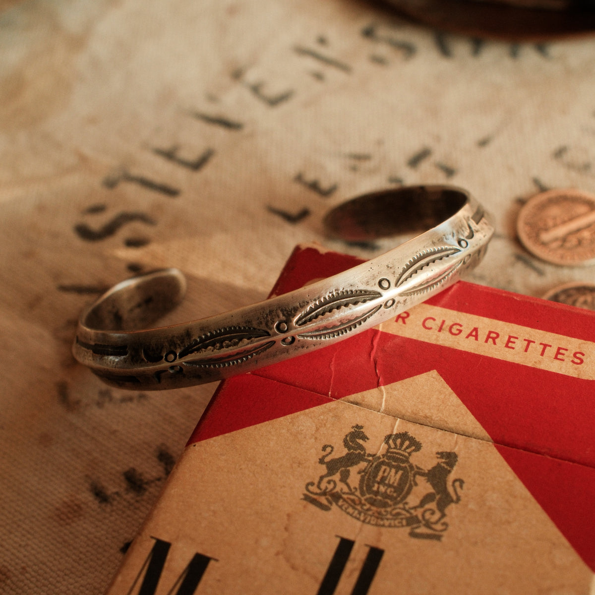 A one-of-a-kind triangular cuff forged from a tufa-cast sterling ingot with the casting texture intact, deeply stamped with arrows at each terminal — view 2
