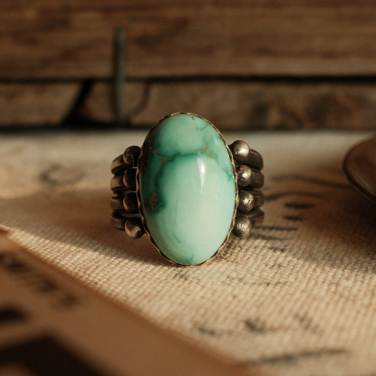 A one-of-a-kind high-domed 12×20mm Fox turquoise in a hand filed serrated bezel on a four-prong split shank, stamped on the back