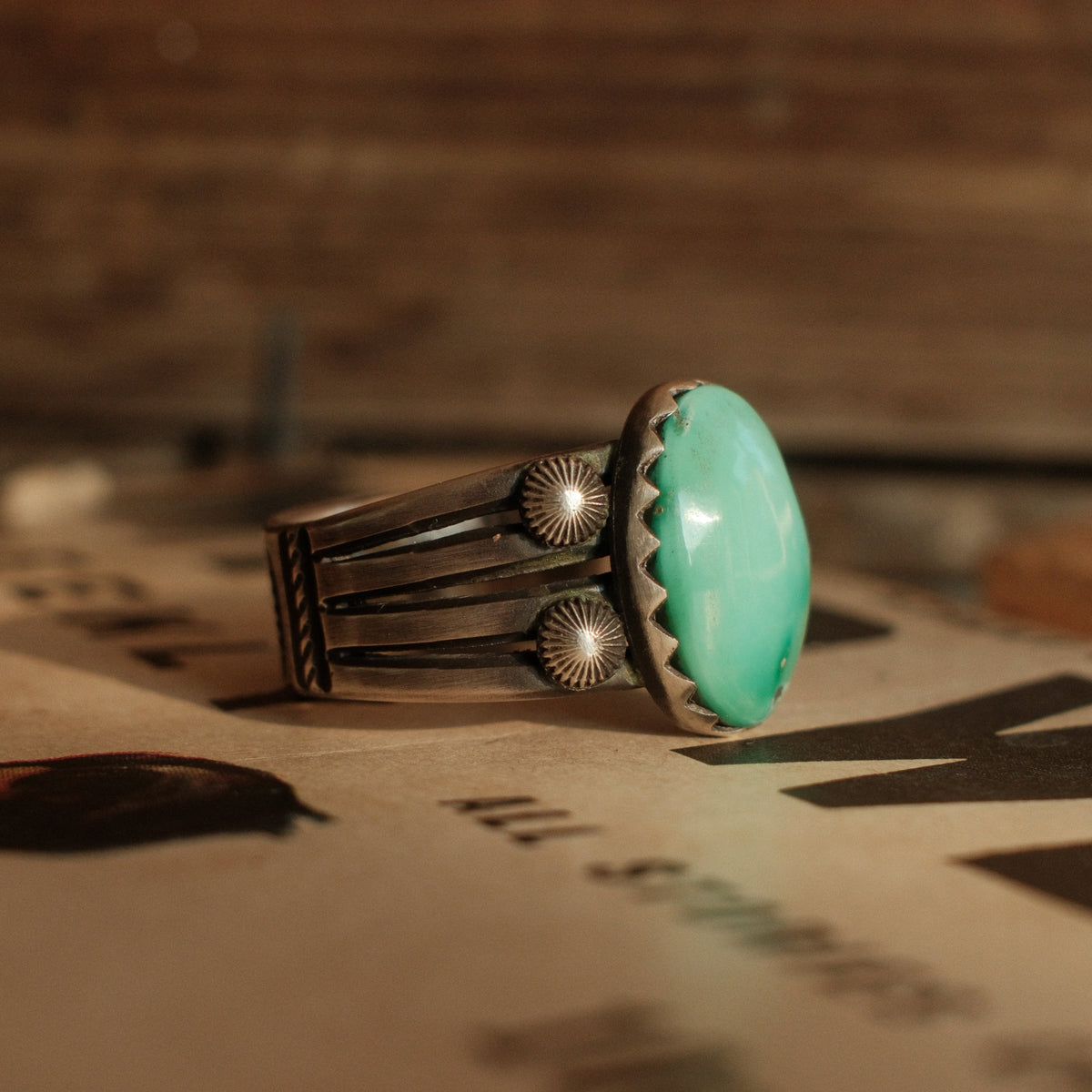 A one-of-a-kind 12×16mm Fox turquoise in a hand filed serrated bezel on a four-prong split shank with starburst conchos, stamped across the back — view 2