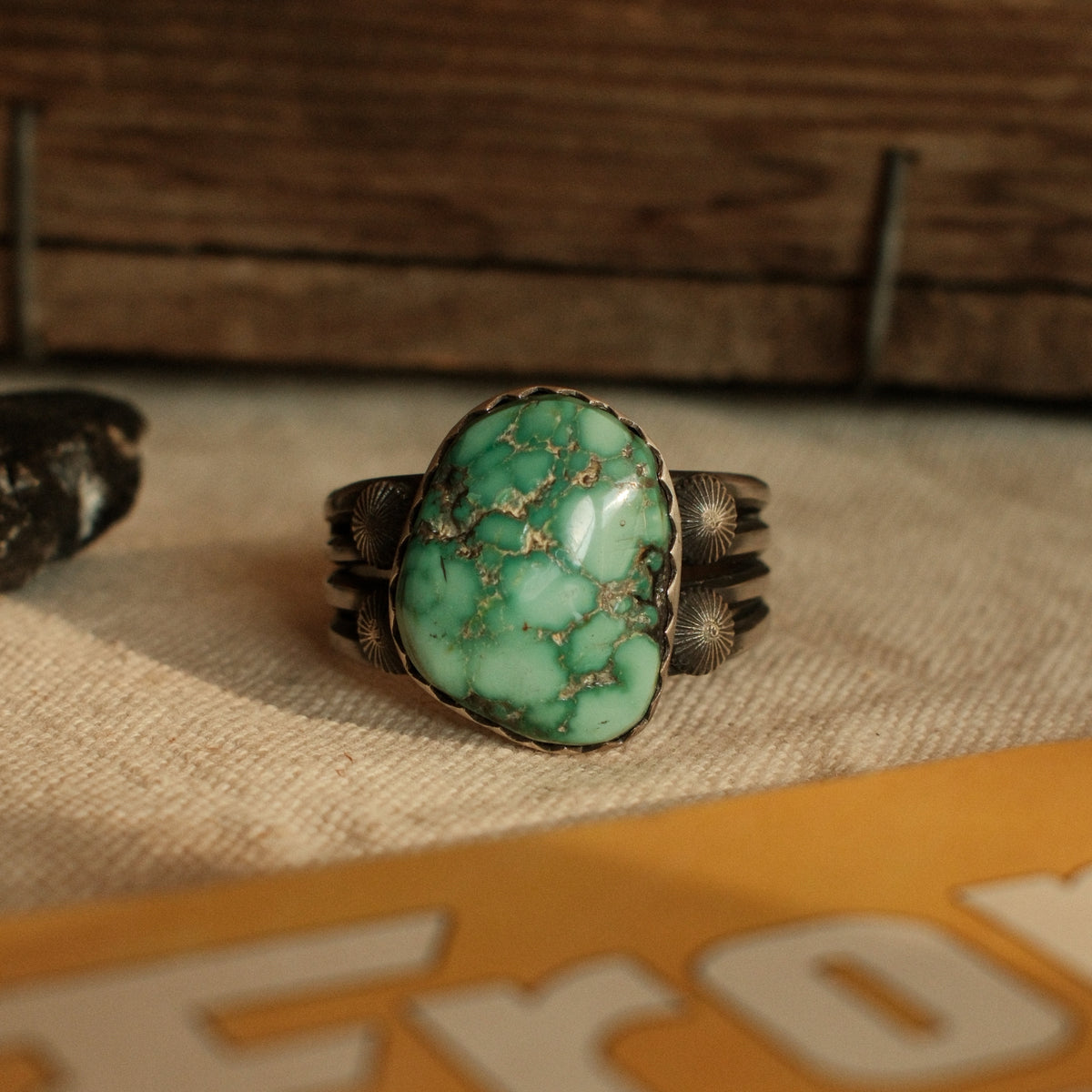 A one-of-a-kind 15×19mm nugget cut Fox turquoise in a hand filed serrated bezel on a four-prong split shank with starburst conchos, stamped across the back