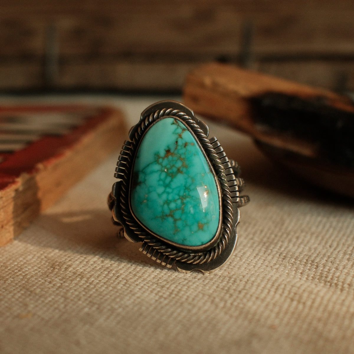 A one-of-a-kind 12×19mm Carico Lake turquoise in a straight bezel inside a twist wire border, on a three-prong stamped split shank