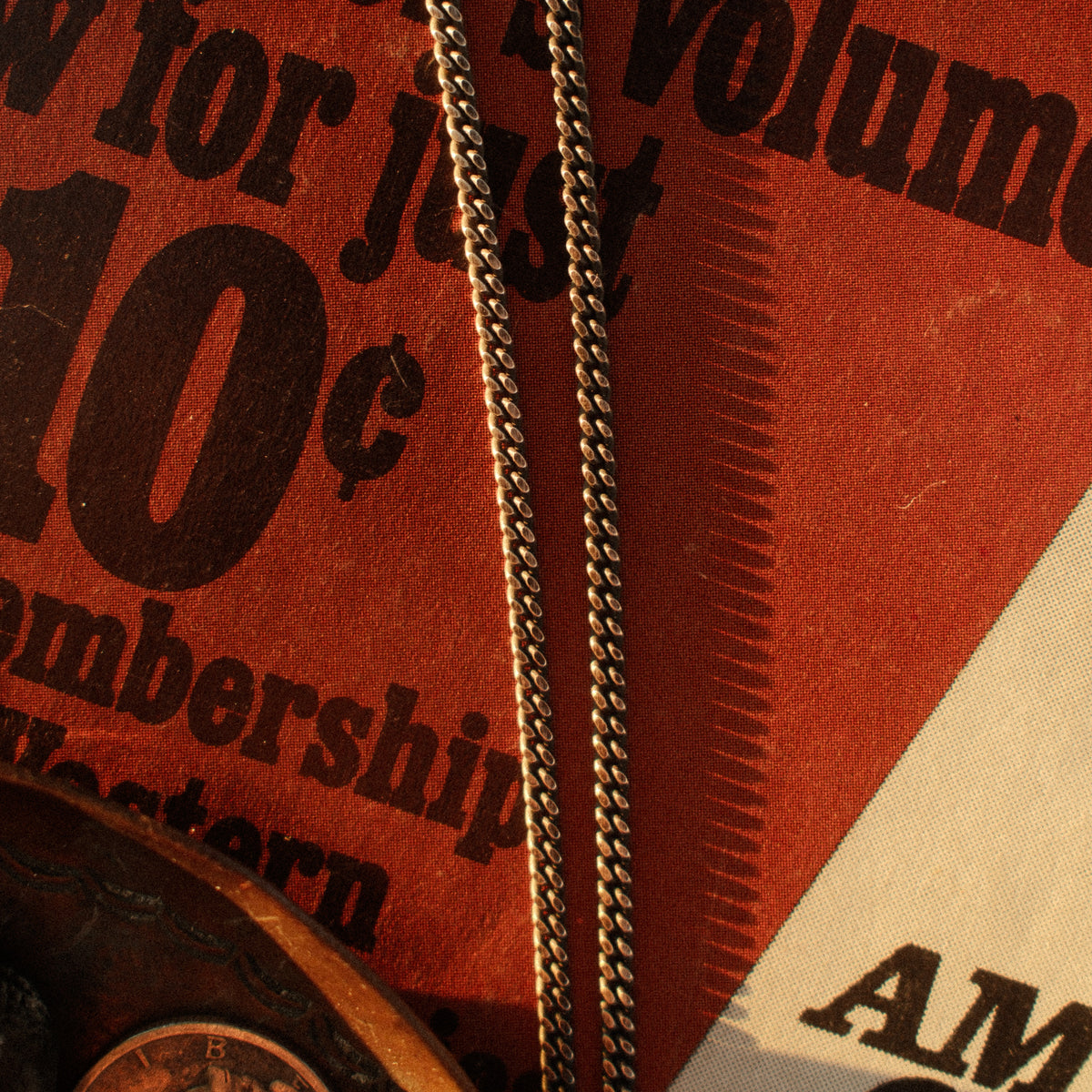 A solid sterling silver curb chain rooted in saddlery and early-hardware design — flat-laying interlocked links with a deep hand-applied patina.