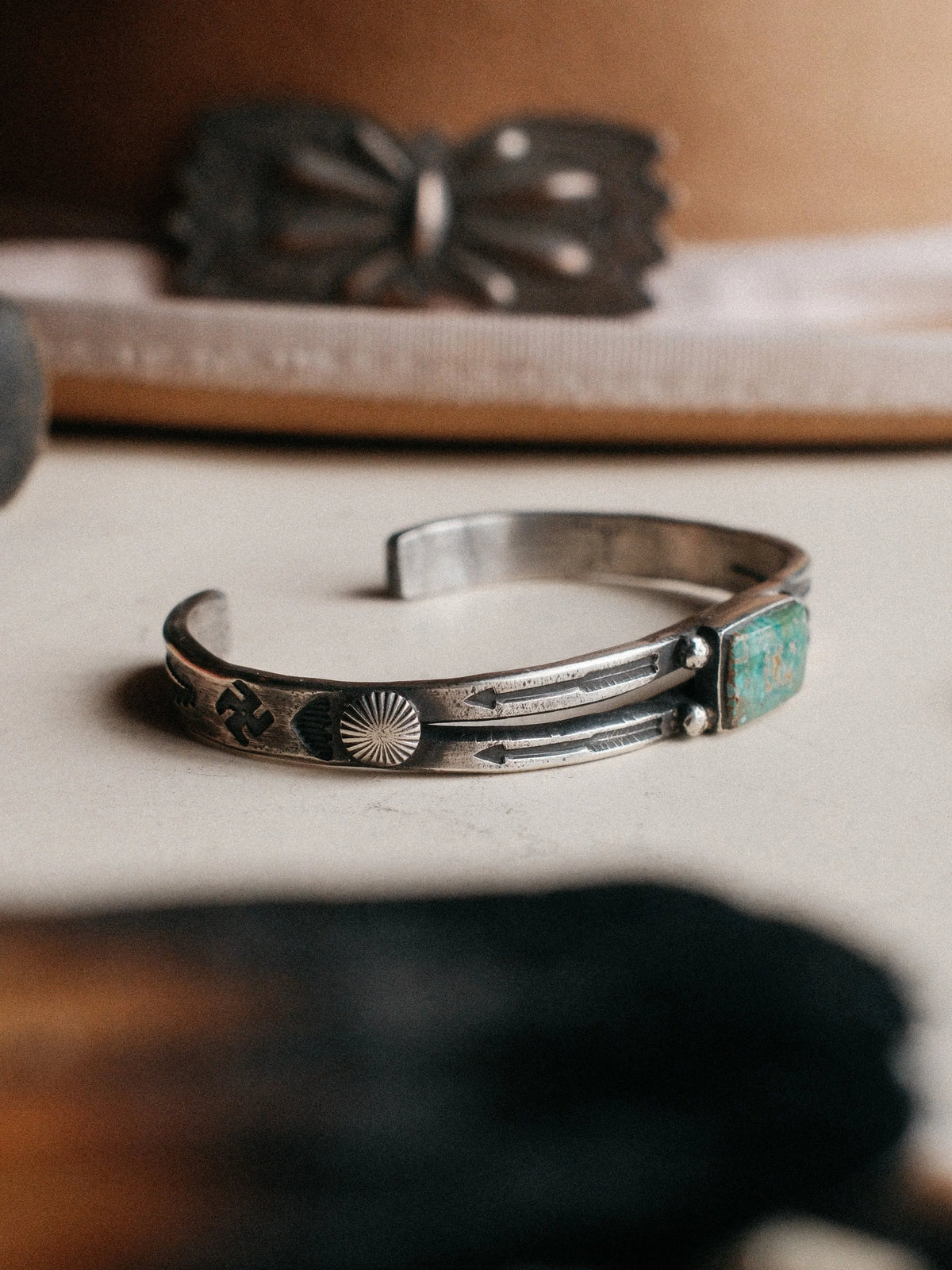A split cuff poured from a tufa-cast ingot and hand-stamped, set with Royston turquoise from Nevada