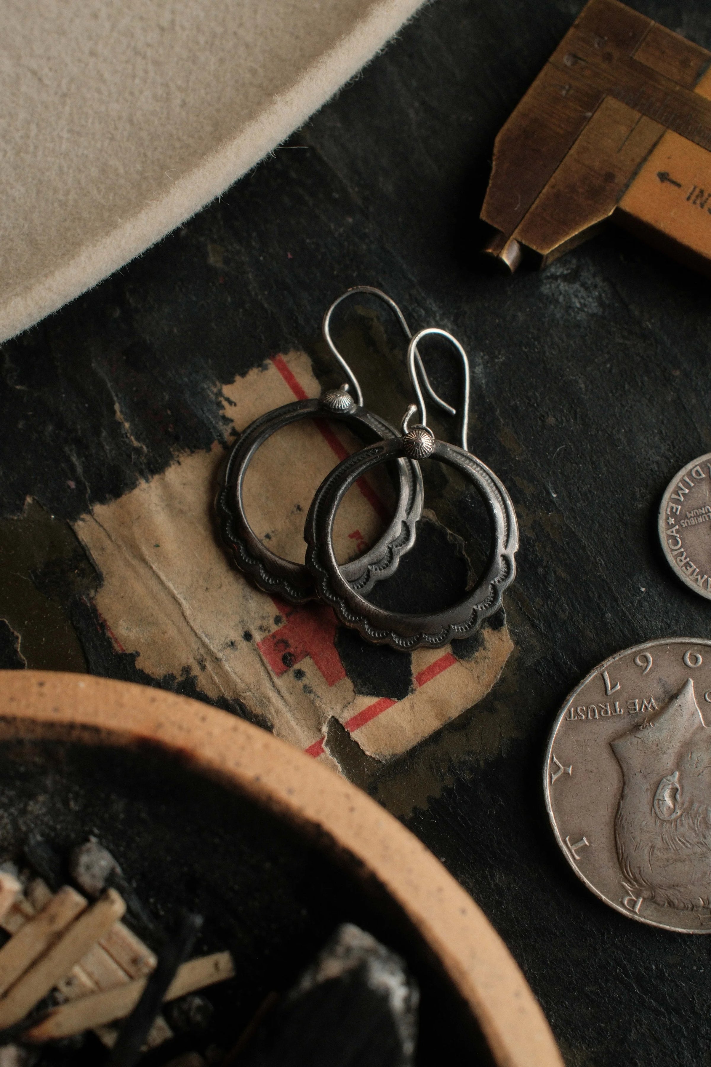 Traditional 1" stamped sterling hoops crowned with conchos and finished with a strong patina