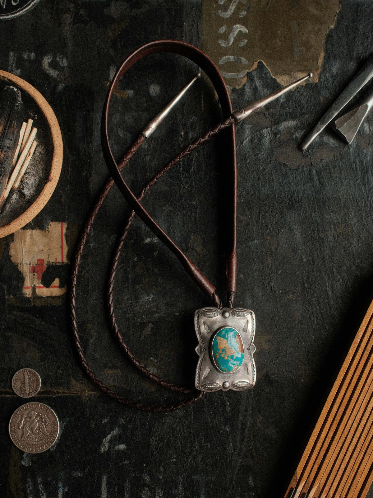 Royston turquoise from Nevada, hand-stamped with bump-outs for dimension and finished with sterling tips on a braided leather cord