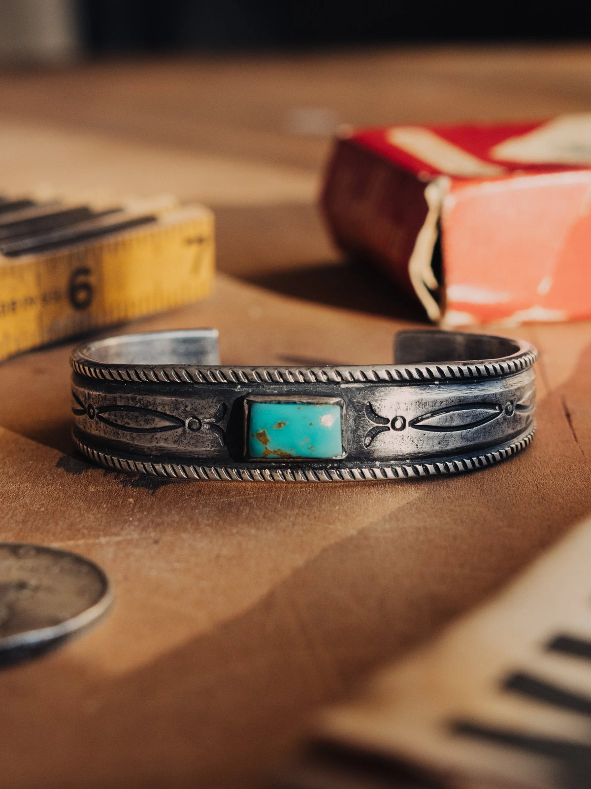 A tufa-cast ingot cuff intricately hand-stamped and set with a deep piece of Manassa turquoise from Colorado's dormant King mine
