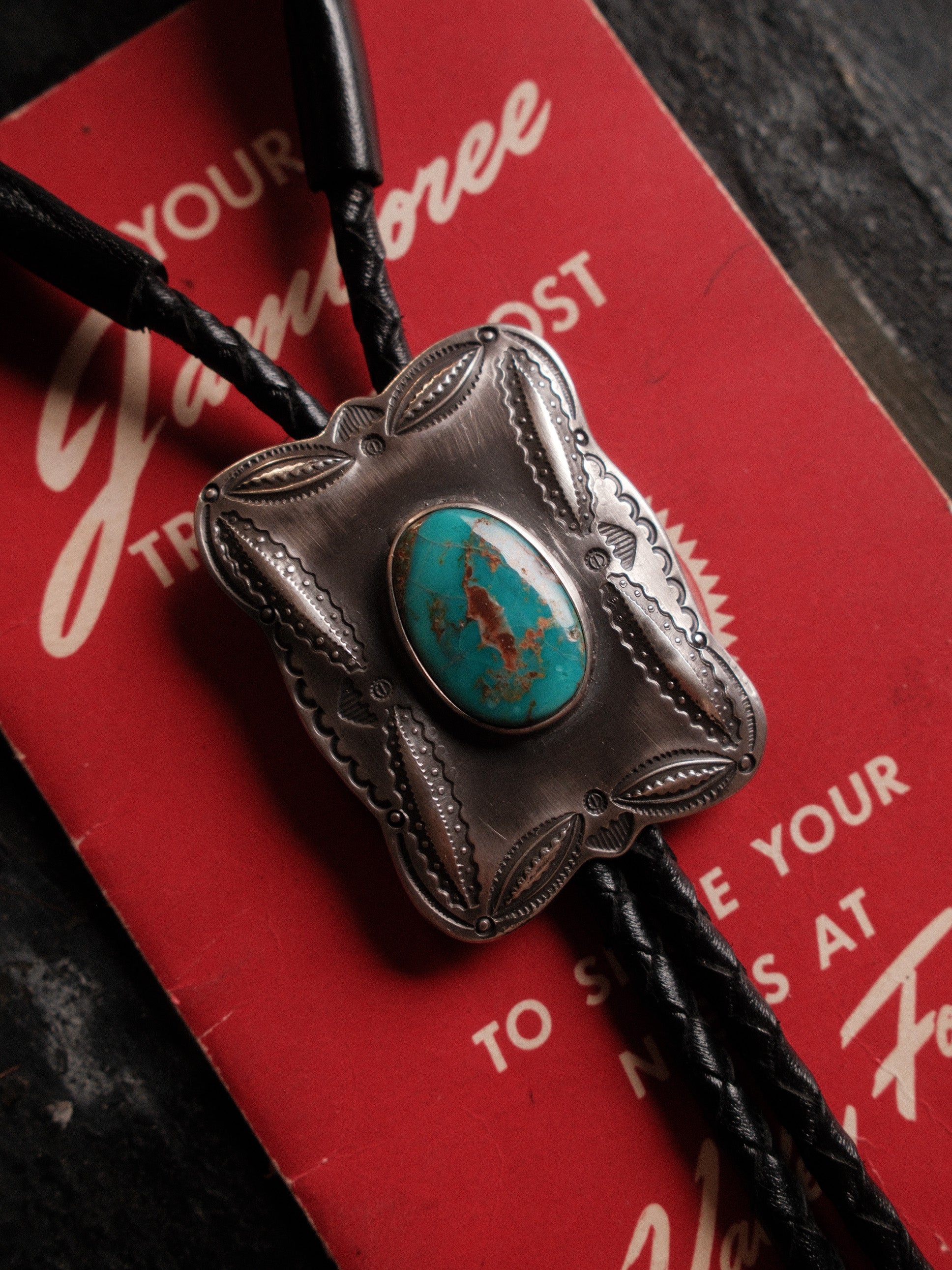 A one-of-a-kind Royston turquoise bolo tie — sterling bump-out stampwork, braided leather cord, sterling end tips