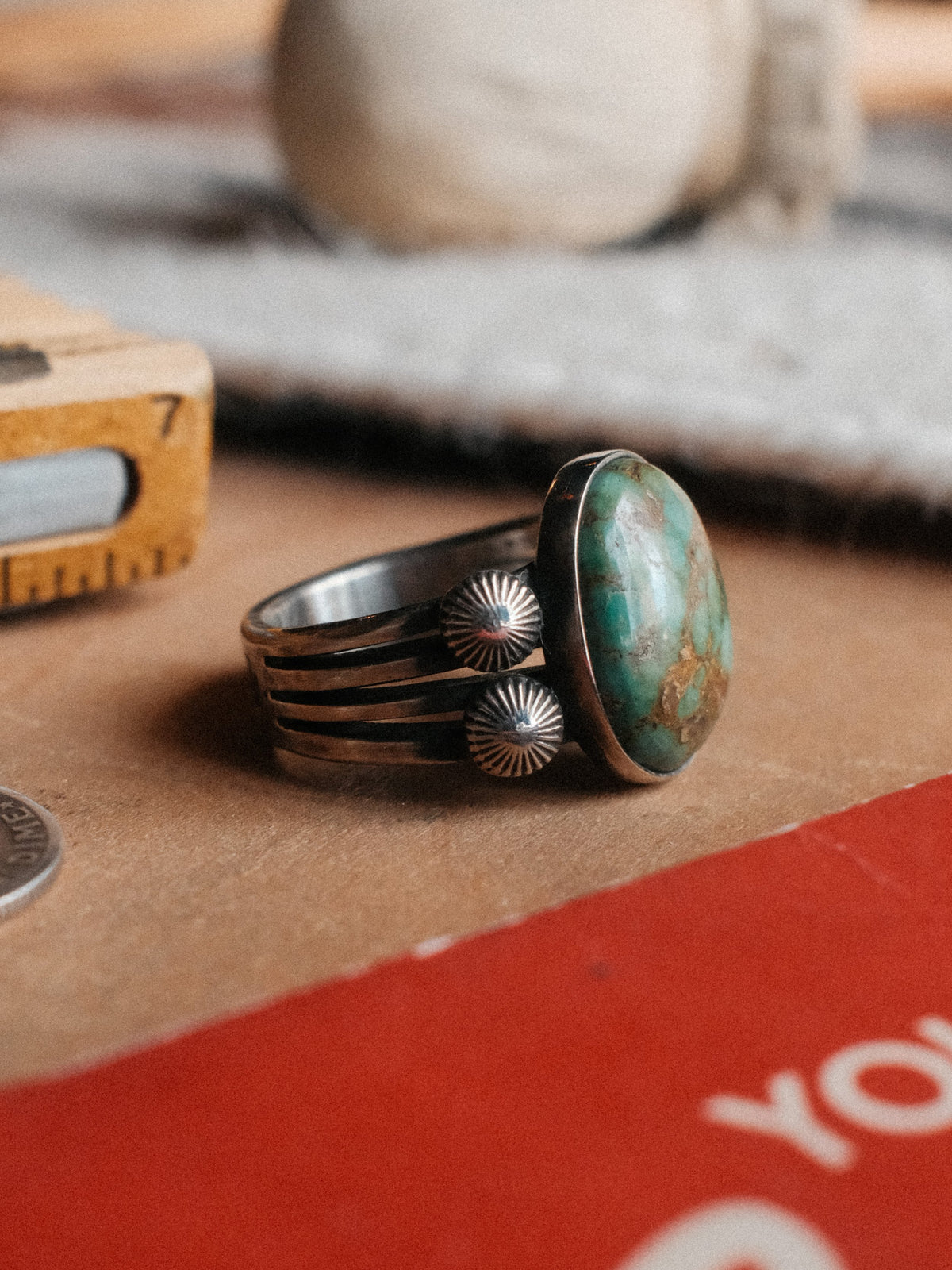 A 16×13mm Royston turquoise stone on a four-prong split shank with sterling concho details, hand-stamped.