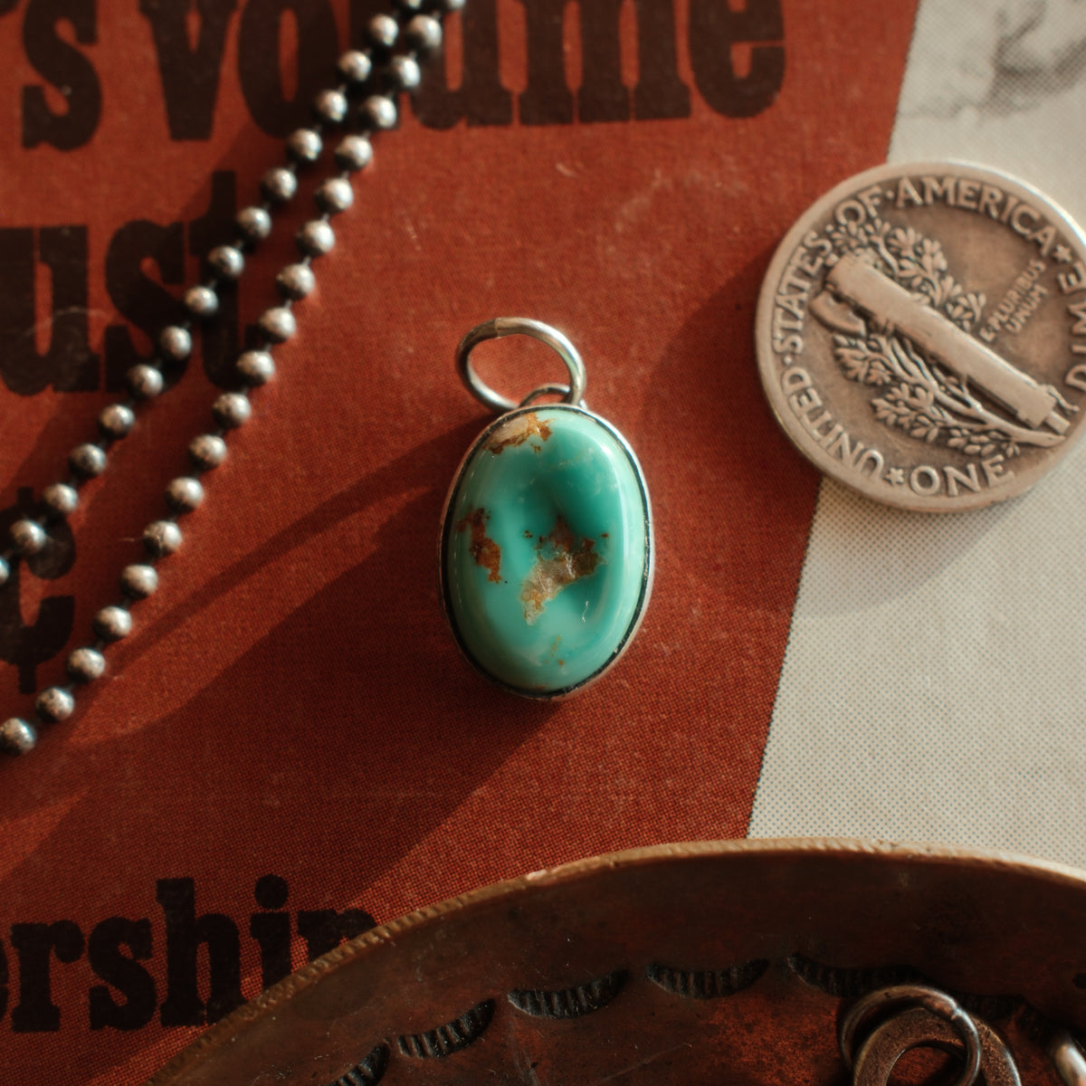 A rough-cut Carico Lake turquoise in a smooth sterling bezel, its natural ridges left intact; each stone differs in matrix and color. Sold as the pendant only.