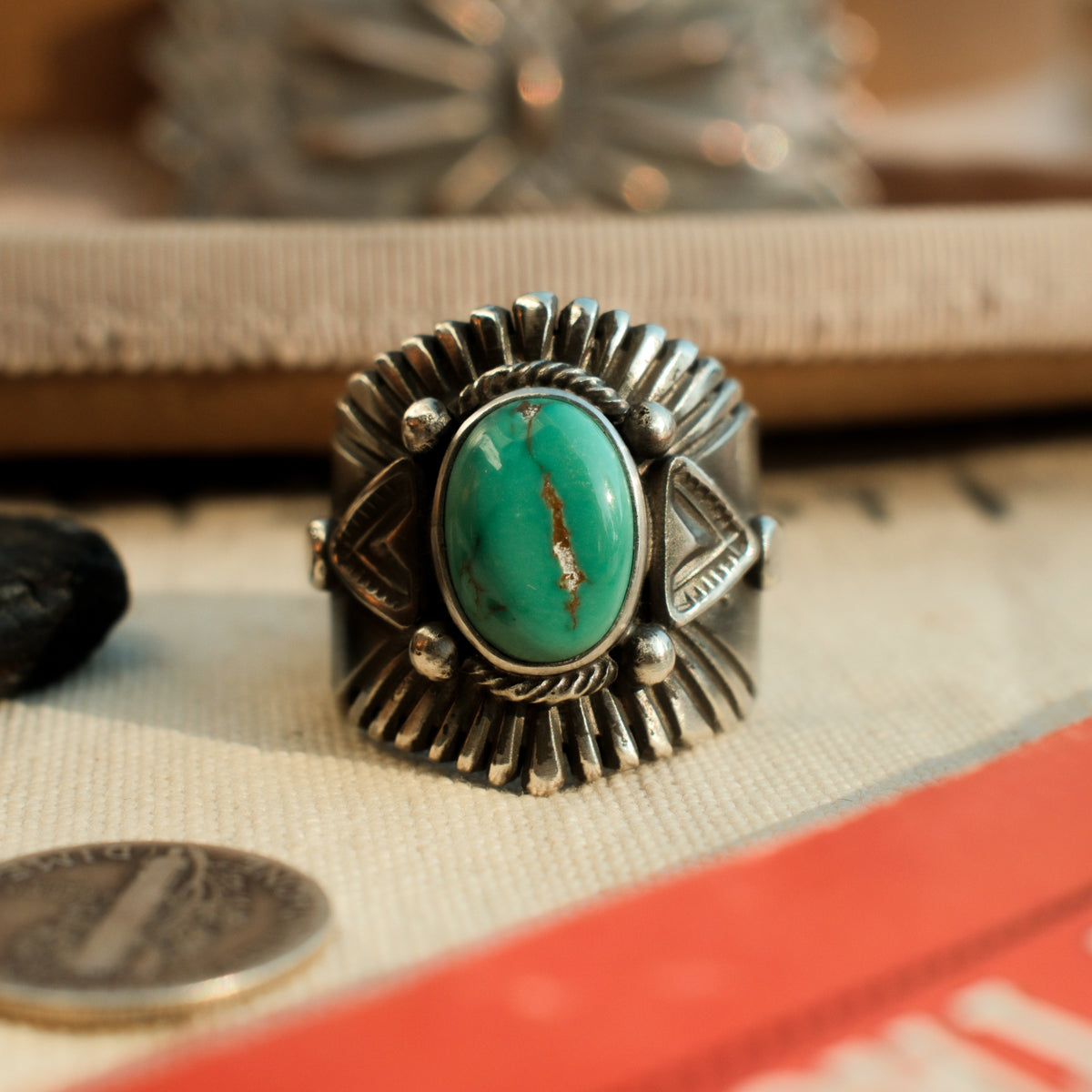 A one-of-a-kind 10×14mm Carico Lake turquoise in a smooth bezel, framed by hand-stamped rays and stamped triangular panels on a wide tapering band.