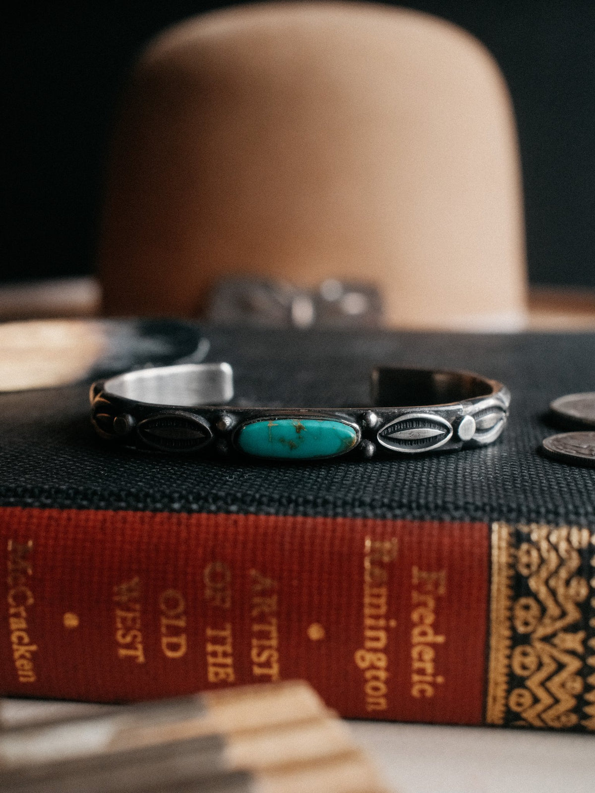 A coin-silver ingot cuff, tufa-cast and intricately hand-stamped, centered on Royston turquoise from Nevada