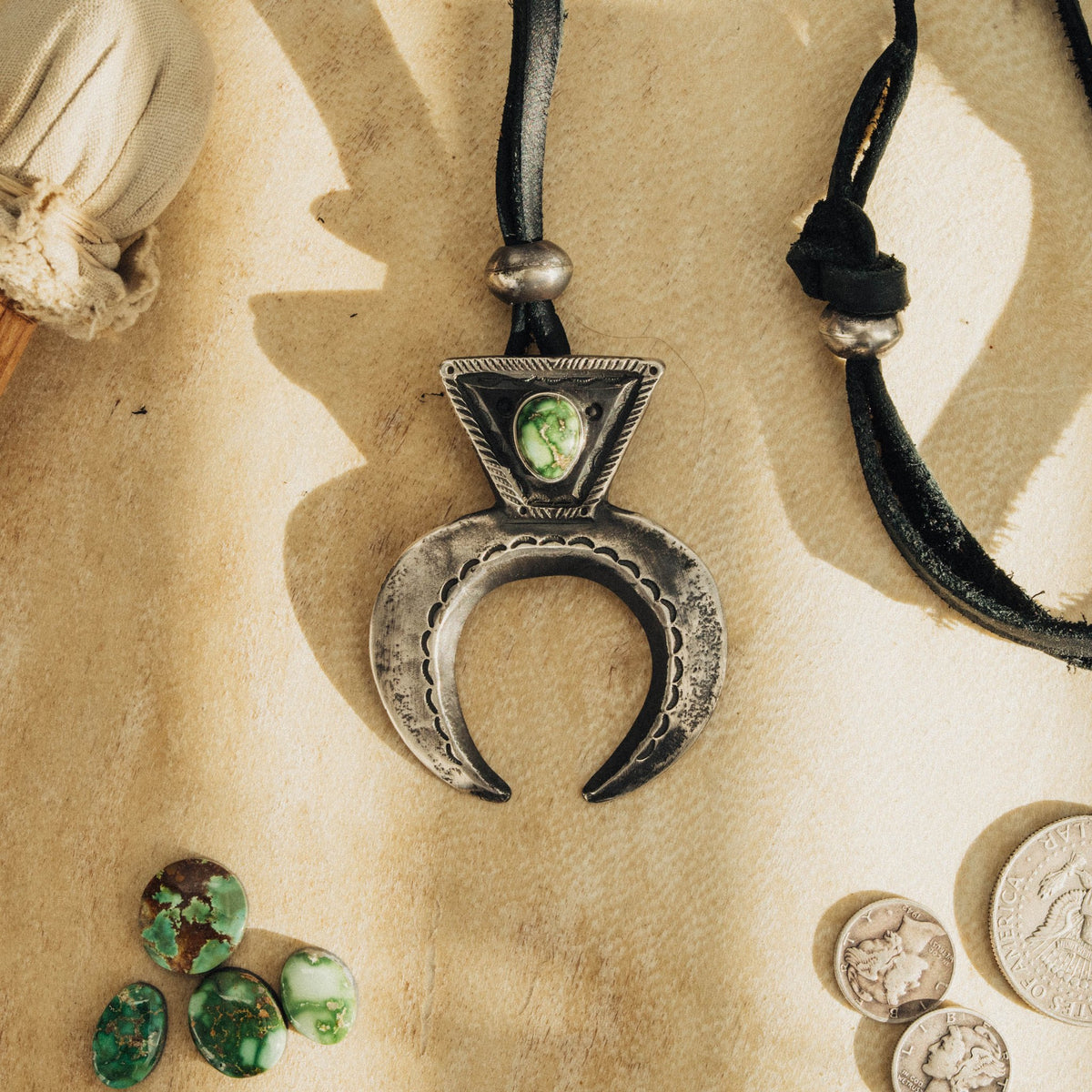 High-grade Sonoran Gold turquoise set on a tufa-cast naja, intricately stamped with our handmade steel stamps and strung on black leather with two handmade adjusting beads
